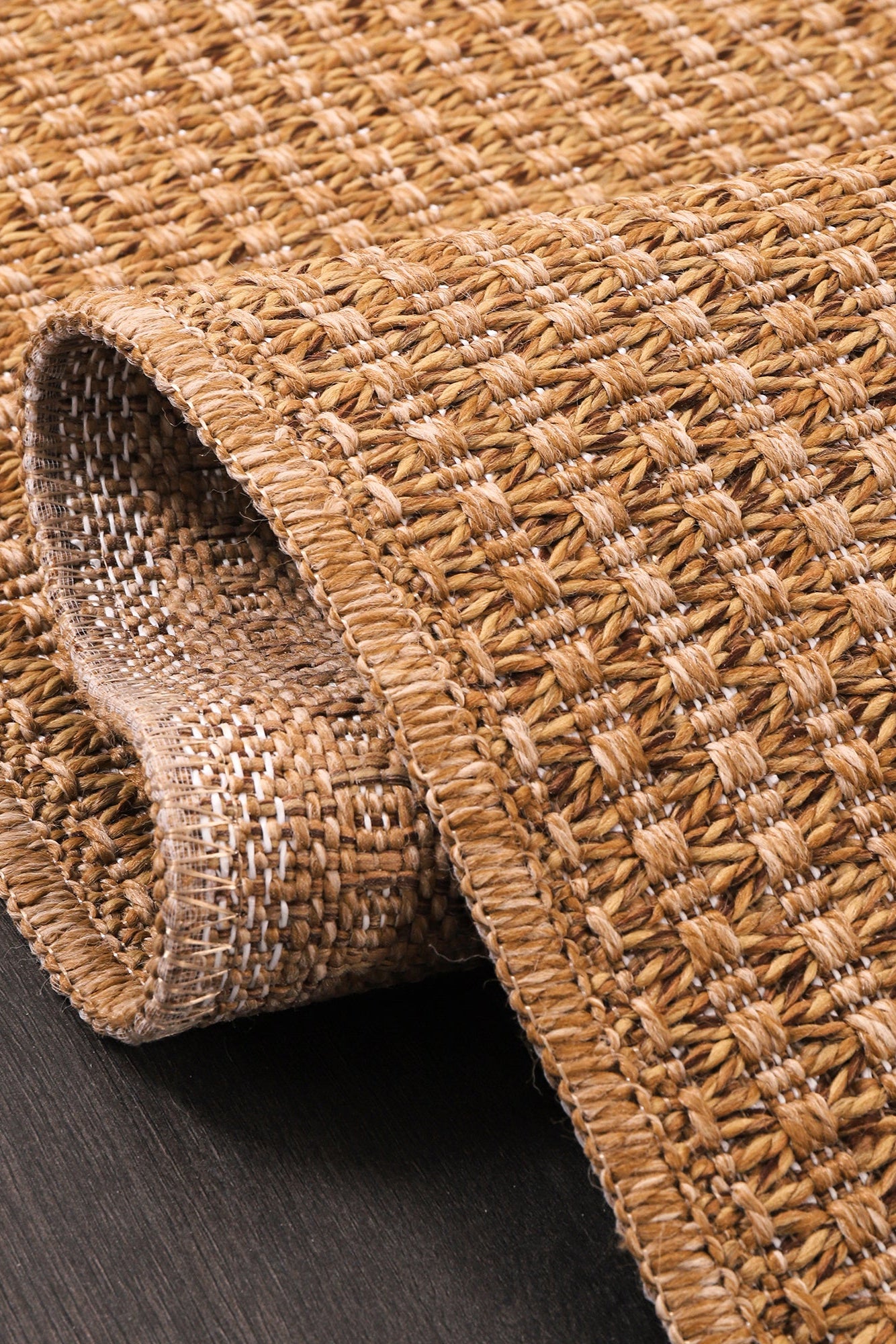Close-up of a textured brown rug on a dark wooden floor