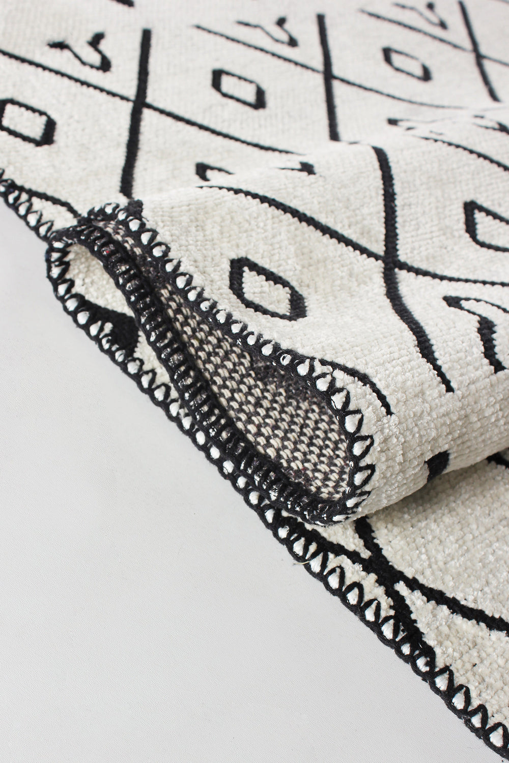 Washable tribal geometric rug by Netline Home featuring black and cream soft chenille with cotton backing on a floor.