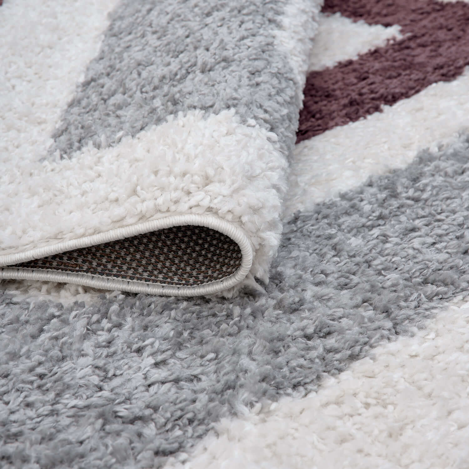 Grey and purple Moodi shaggy contour runner rug from The Rugs, folded to show its plush, textured surface and soft fibers.