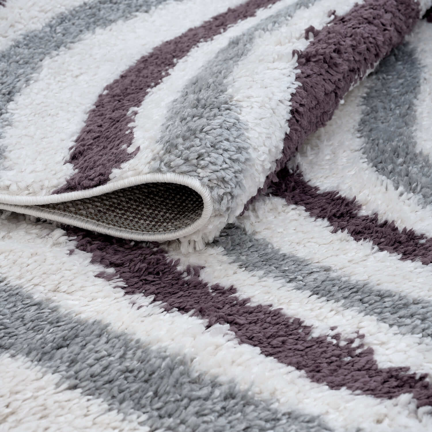 Folded Moodi Shaggy Grey and Purple Smokeberry Runner Rug by The Rugs, showing its soft, plush shaggy texture and vibrant colors.